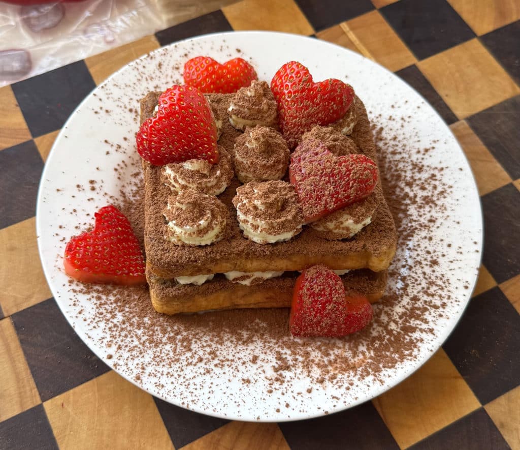 Tiramisu French Toast: A decadent twist on a classic breakfast, featuring coffee-soaked bread, creamy mascarpone, cocoa powder, and strawberries.