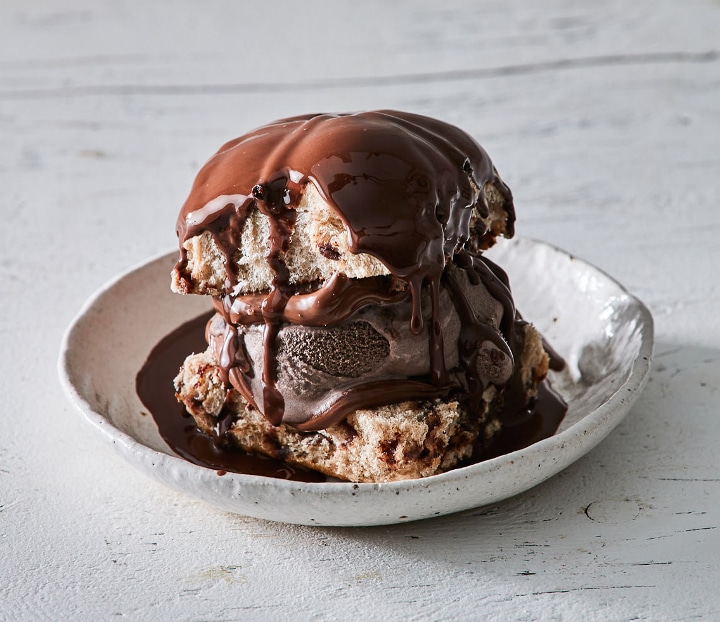 A Choc Chip Hot Cross Bun Ice Cream Sandwich filled with Nutella and chocolate ice cream, drizzled with Ice Magic.